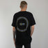 schwarzes oversized "Techno Tribe Circle" Raver T-Shirt von hinten, getragen von einem Mann