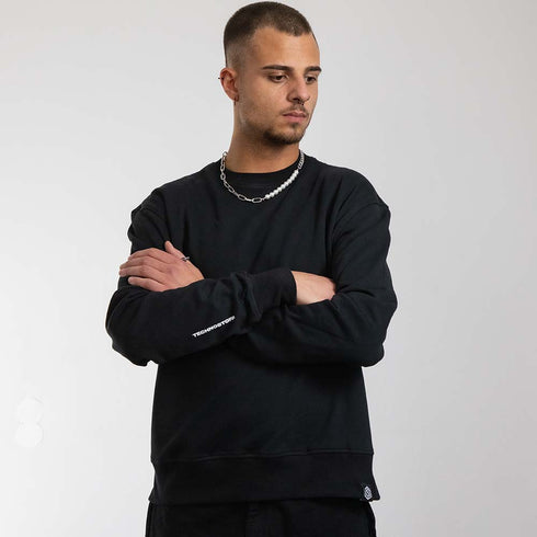 schwarzer oversized "Stoff hoch 4" Raver Sweater von vorne, getragen von einem Mann mit verschränkten Armen