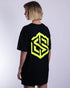 "NYS" oversized T-Shirt für Raver in schwarz mit neon gelbem Technostoff Logodruck, getragen von einer Frau, von hinten fotografiert