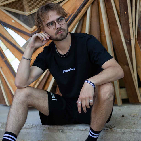 Männliches Model im Technostoff Embroidery Backseam T-Shirt mit Stick auf der Brust und Detailprints in schwarz