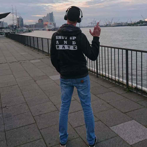 Raver im Techno Shut Up And Rave Windrunner von Technostoff. Foto von hinten, im Hintergrund Hamburg