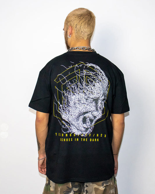 Raver from behind with Technostoff Echoes In The Dark T-shirt, skull artwork with yellow lettering