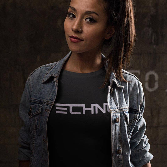 Female raver wearing the black Technostoff Techno T-shirt with denim jacket, TECHNO lettering on chest