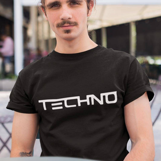 Raver wearing the black Technostoff Techno T-shirt with white TECHNO lettering in a cafe