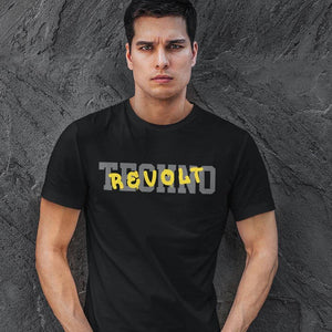 Raver wearing the black Technostoff Techno Revolt T-shirt with yellow REVOLT print in front of dark stone wall