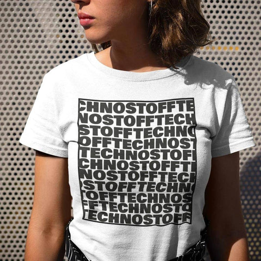 Female raver wearing the white Technostoff Square T-shirt with repeating TECHNOSTOFF text block in front of metal wall