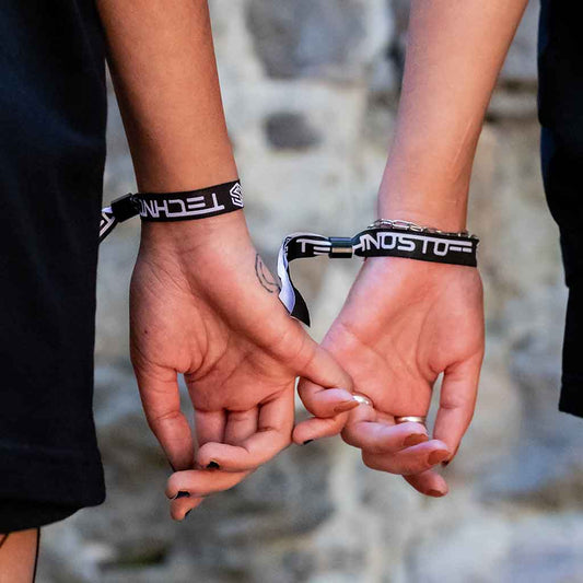 Two female ravers wearing Technostoff fabric wristbands, hands intertwined